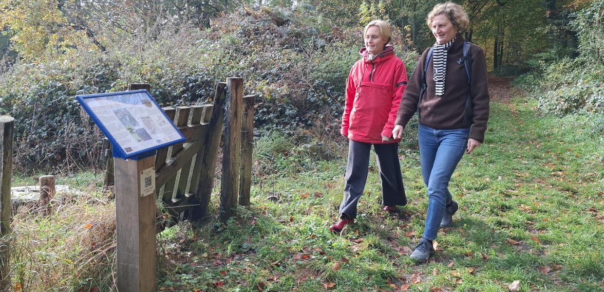 To kvinder læser skilt om vandrefortællinger langs Øhavsstien